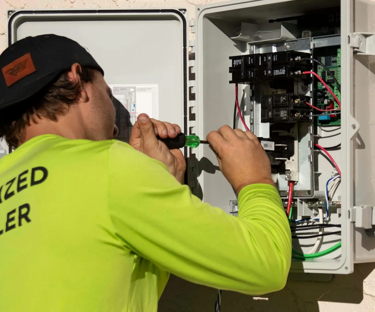 Elektriker arbeitet mit dem Schraubenzieher an einem Verteilerkasten